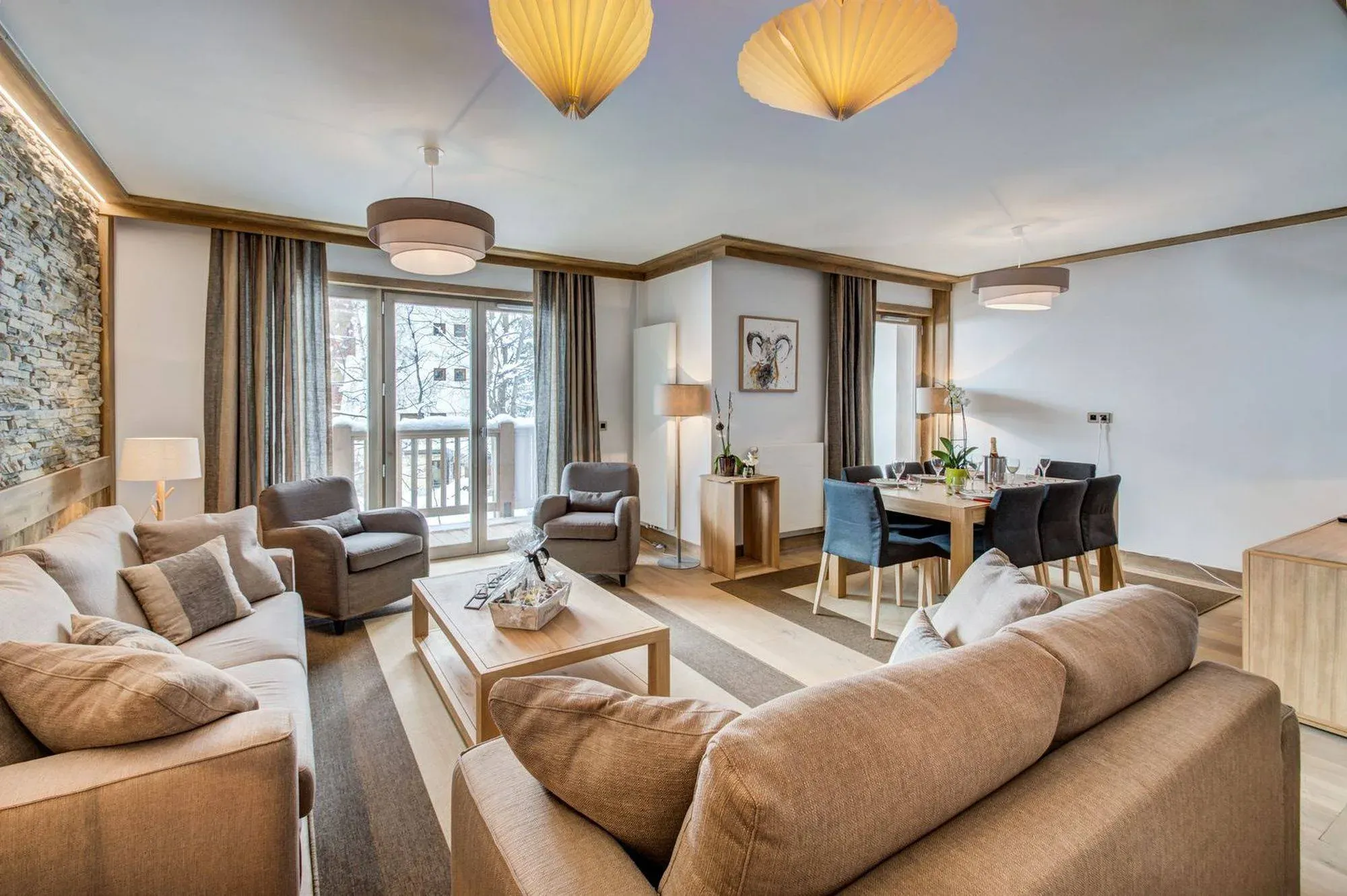 Living room with two sofas, two armchairs and stone feature wall, dining table beyond
