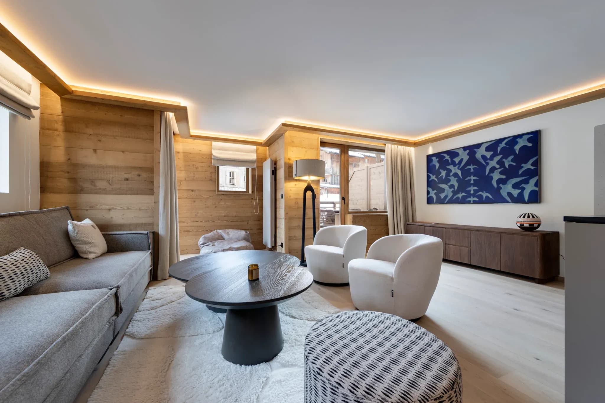Living room with grey sofa, two swivel armchairs and balcony doors
