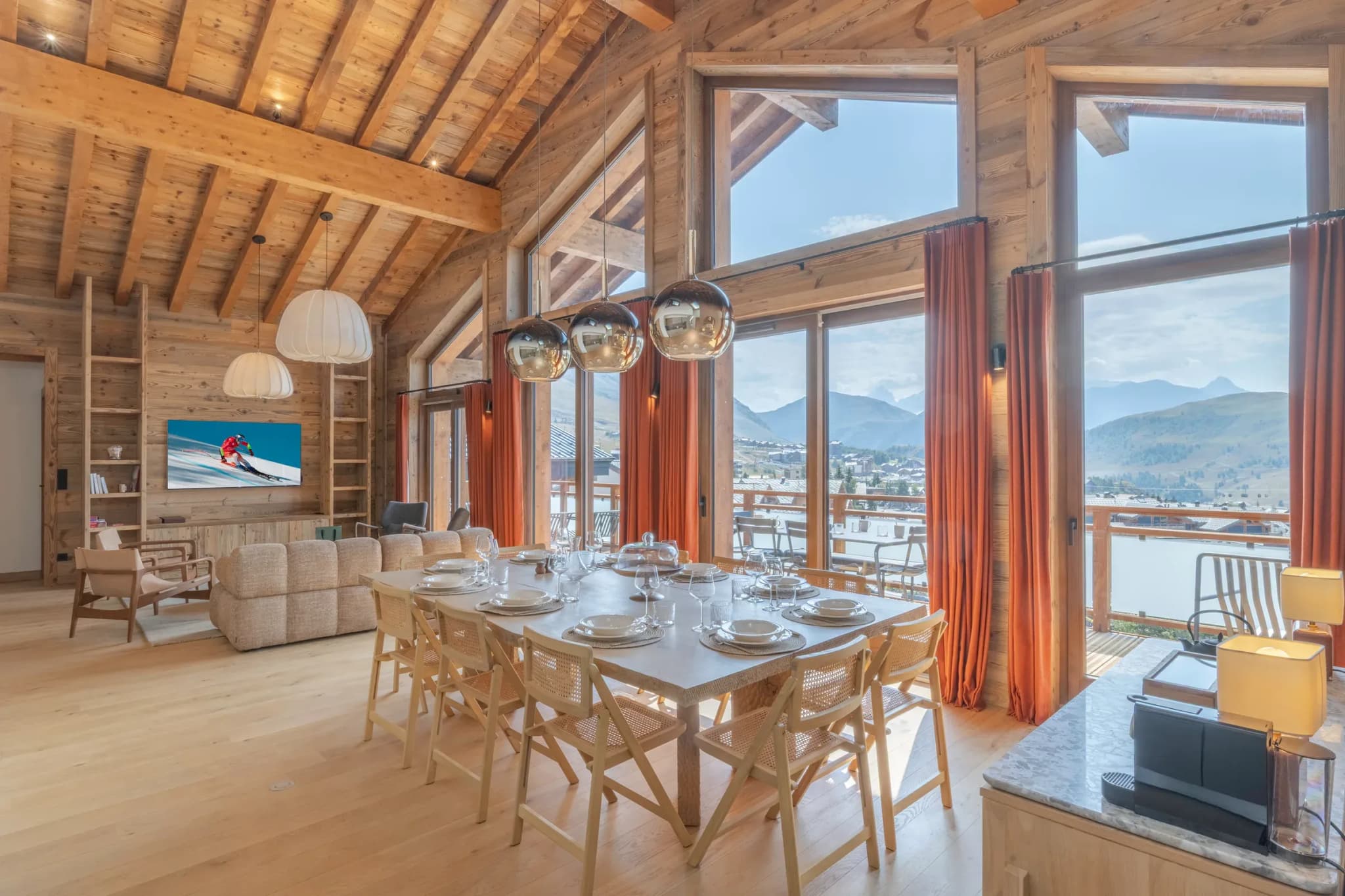 Open-plan dining table seating ten, with lounge and mountain views through tall windows
