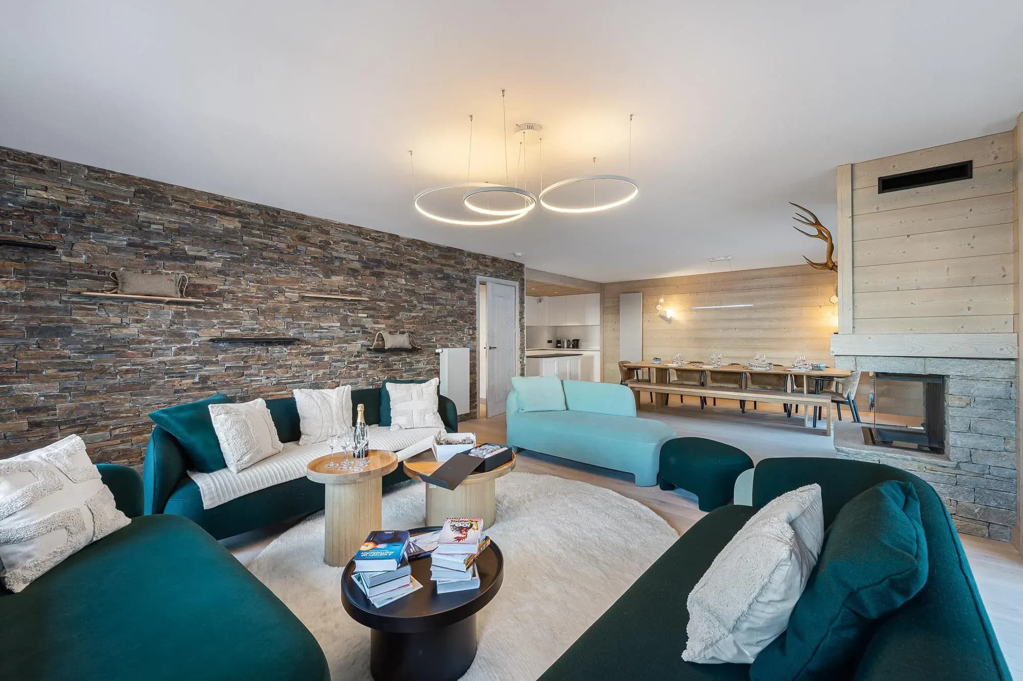 Living room with green sofas, stone feature wall and double-sided fireplace