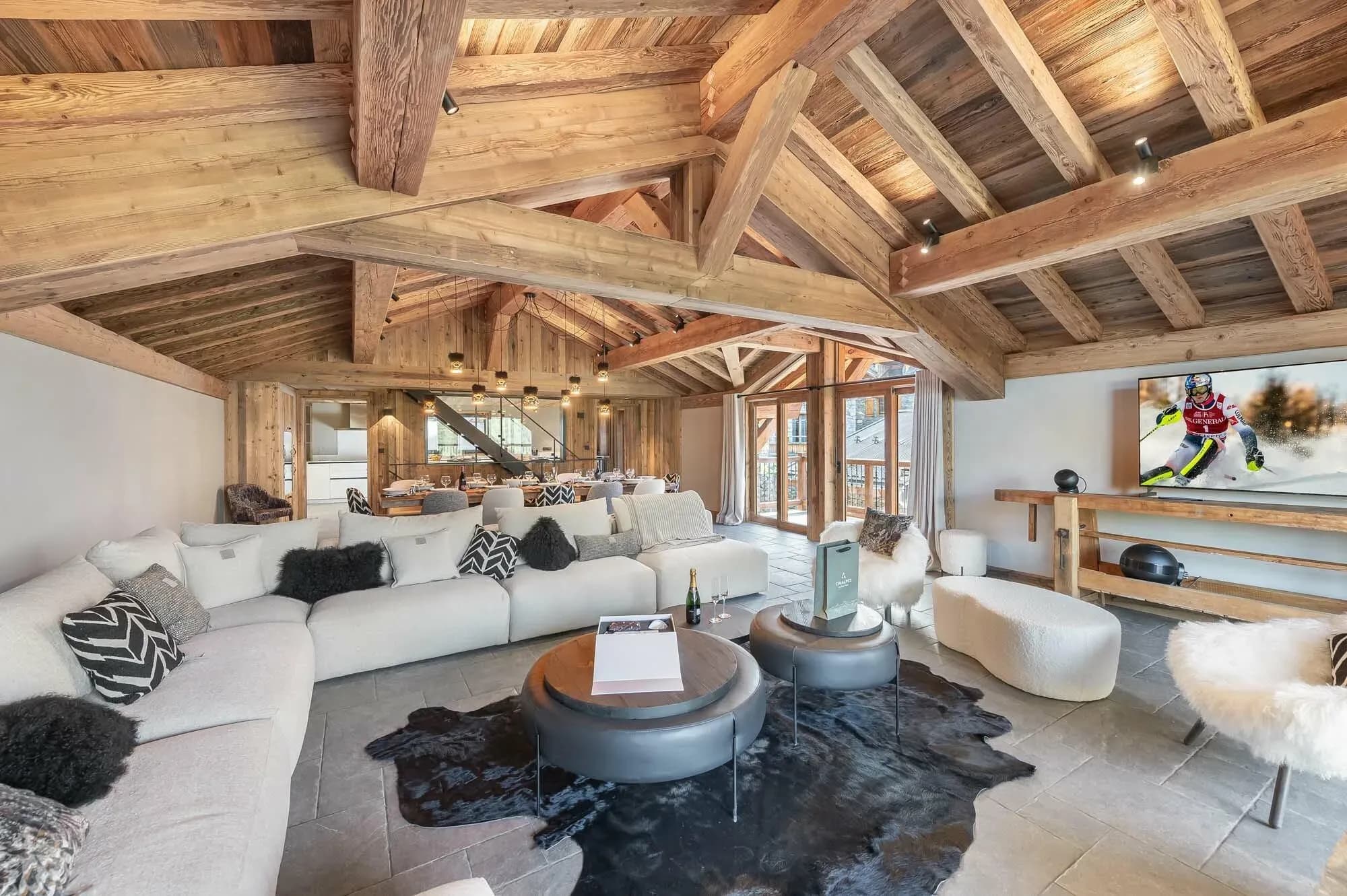Living room with large corner sofa, round coffee tables, wall-mounted TV and dining table beyond