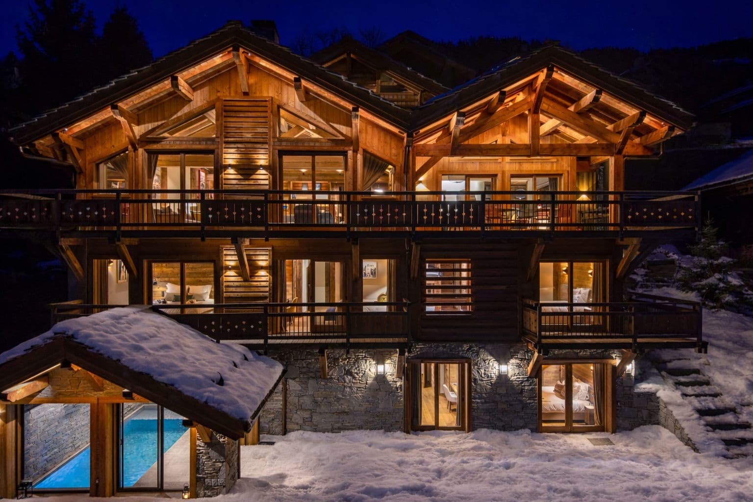 Luxury chalet exterior at dusk; heated pool house visible at ground level