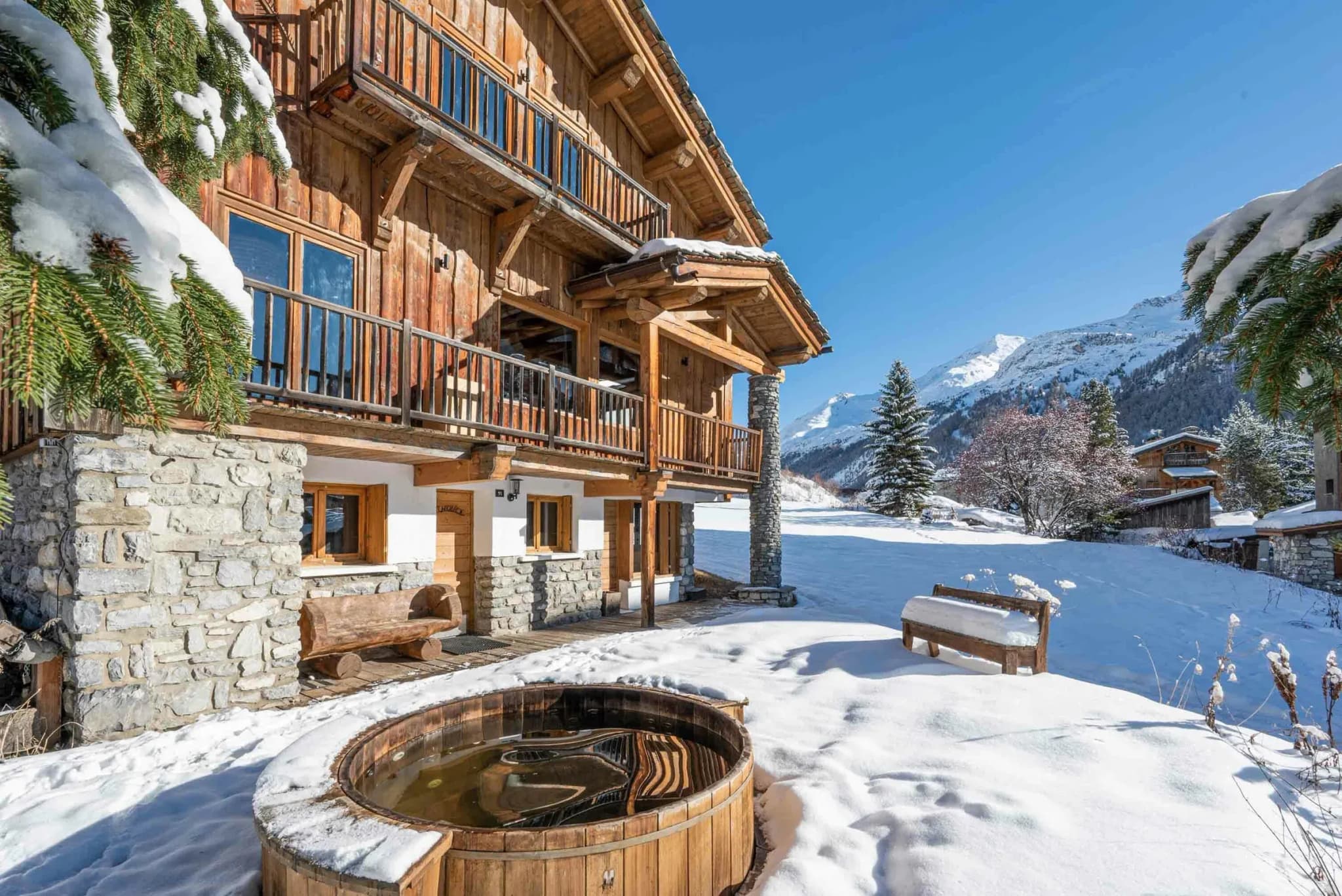 Chalet exterior with wooden hot tub in the snow and mountain view