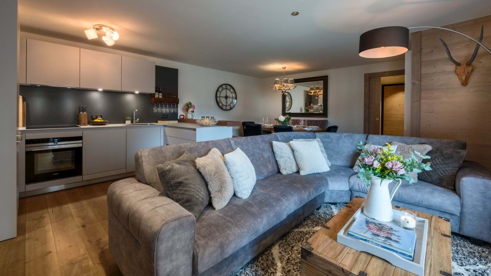 Open-plan living area featuring corner sofa, breakfast bar, and integrated kitchen appliances