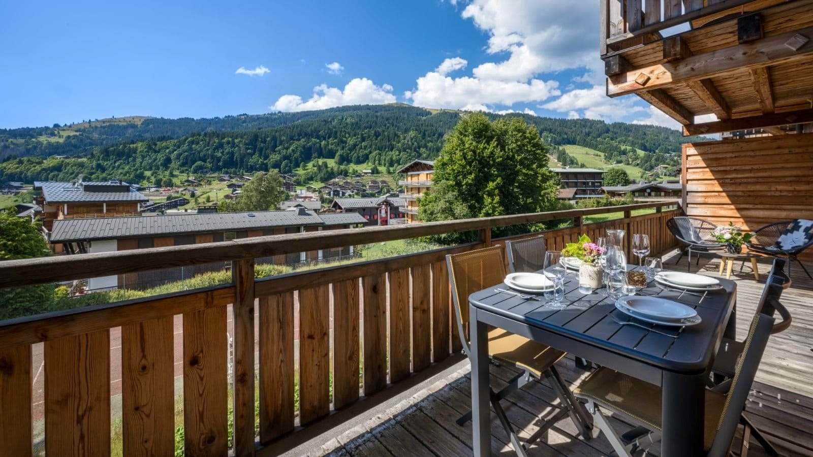 Private balcony with four-person dining table and mountain village views