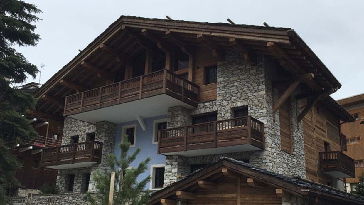 Stone and timber chalet exterior featuring private balconies on multiple levels