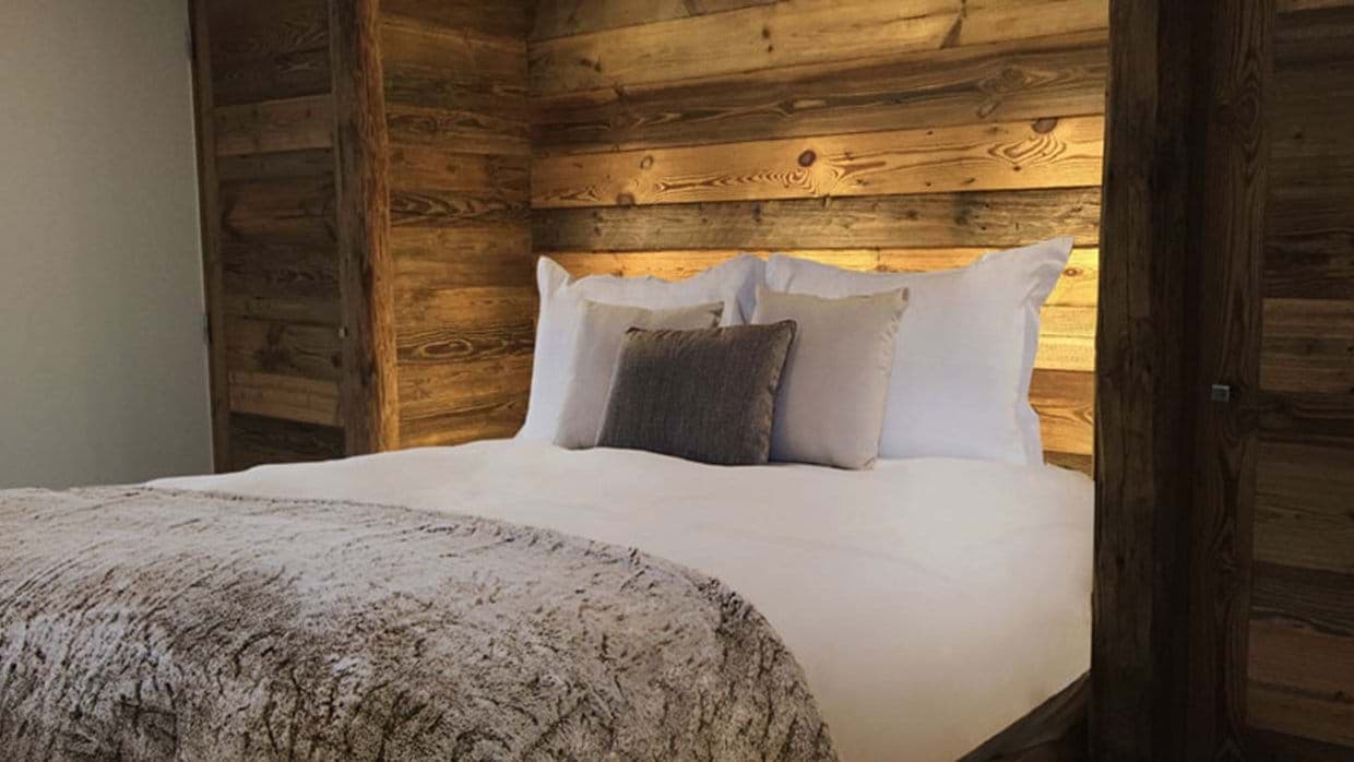 Guest bedroom with reclaimed wood accent wall and integrated headboard lighting