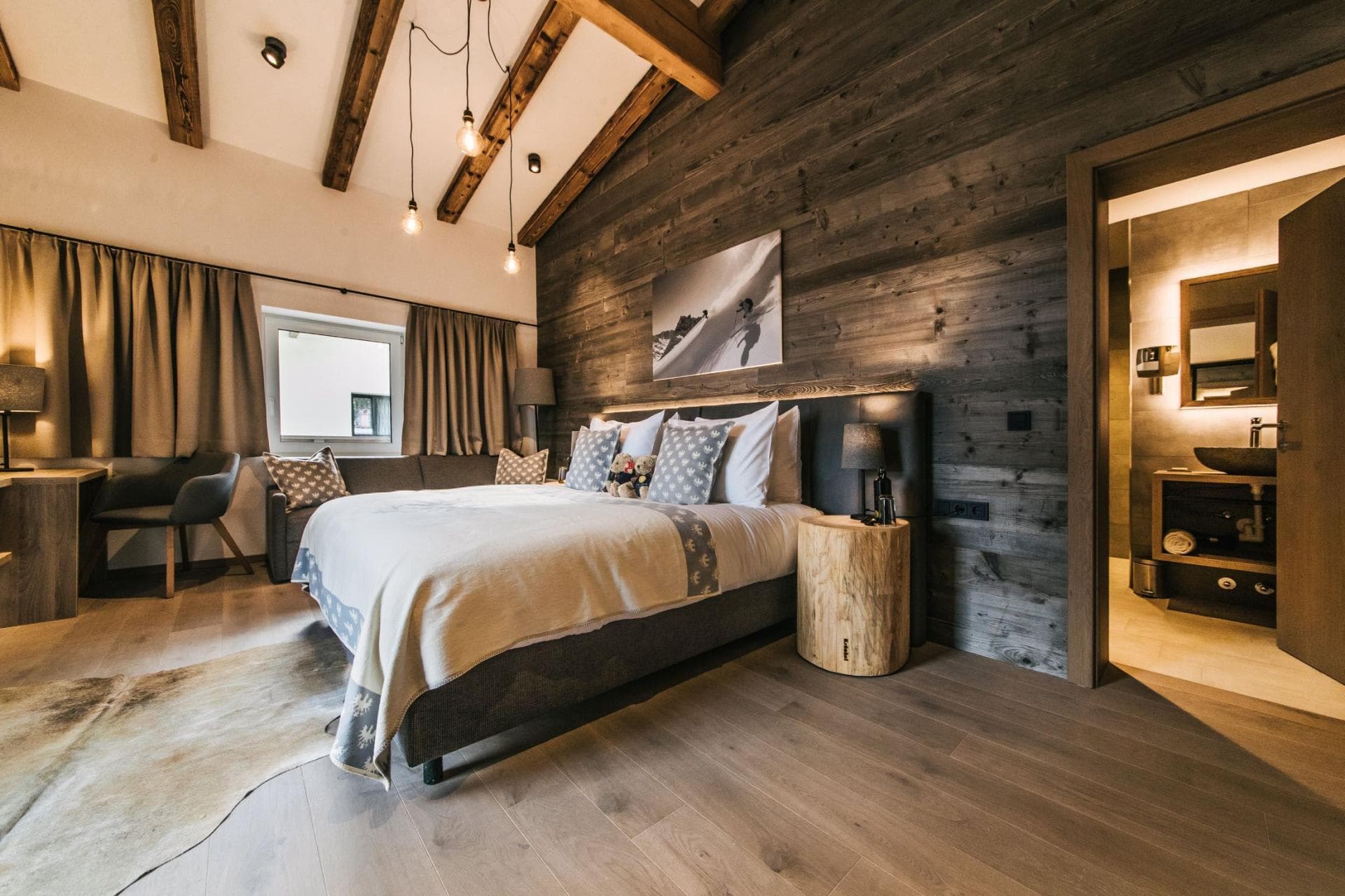 Primary bedroom with king bed, vaulted ceiling with exposed beams, and ensuite bathroom