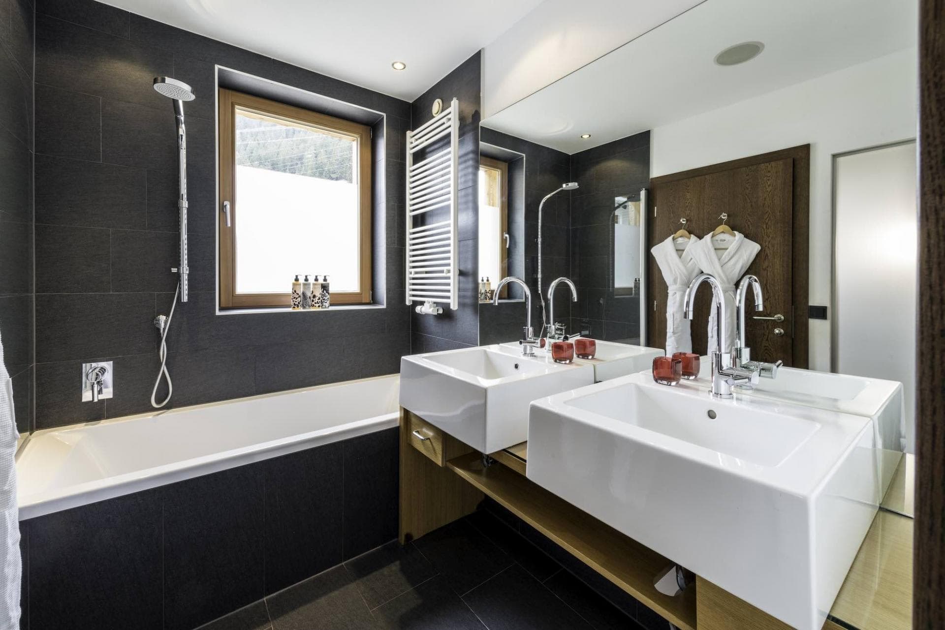 Bathroom with dual vessel sinks, heated towel rail, and soaking tub