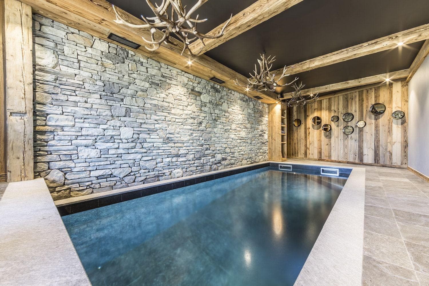 Indoor heated pool with natural stone wall and antler chandeliers
