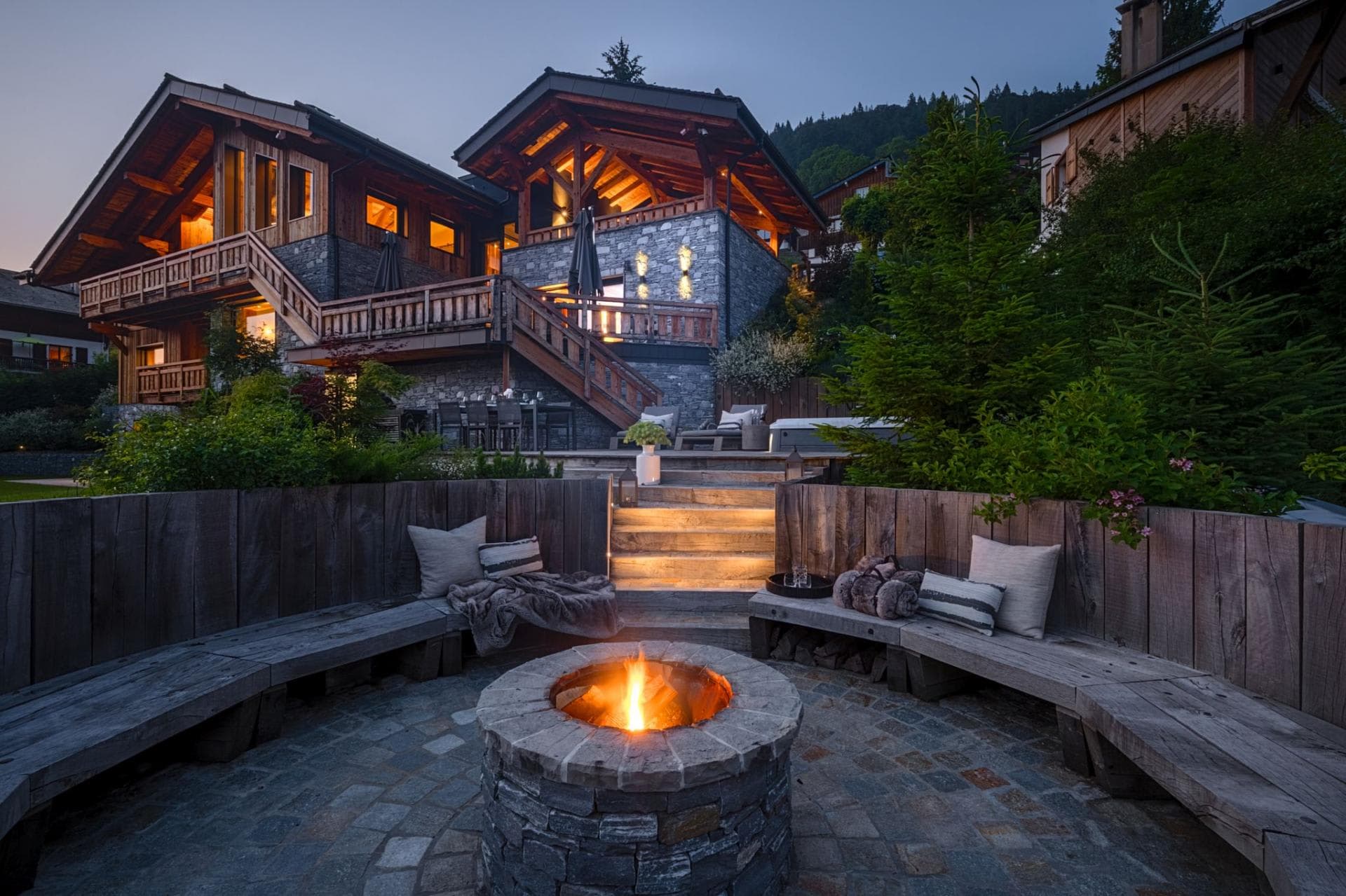 Stone fire pit with built-in bench seating and chalet views