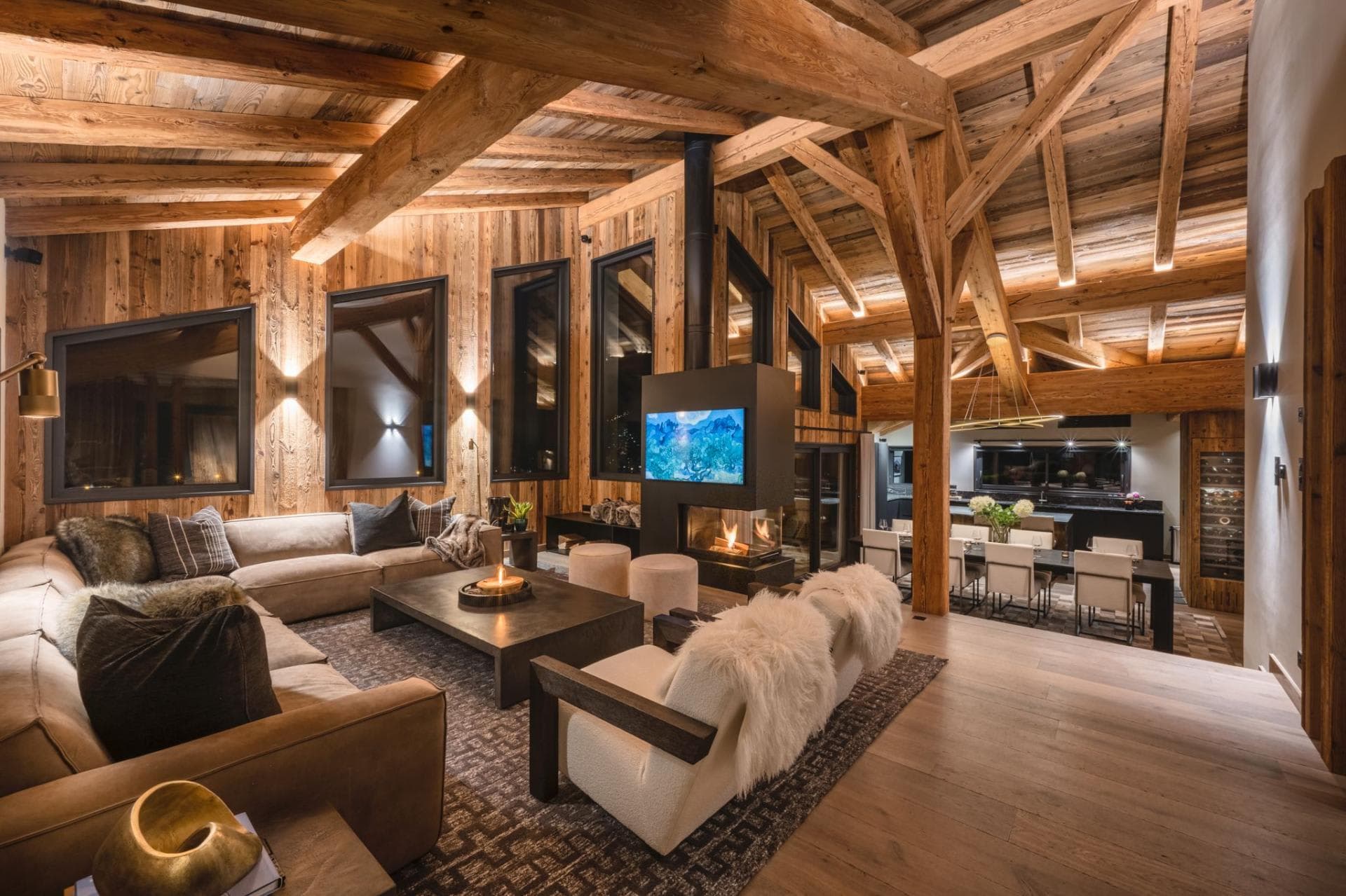 Open-plan living area with three-sided gas fireplace and vaulted timber ceilings