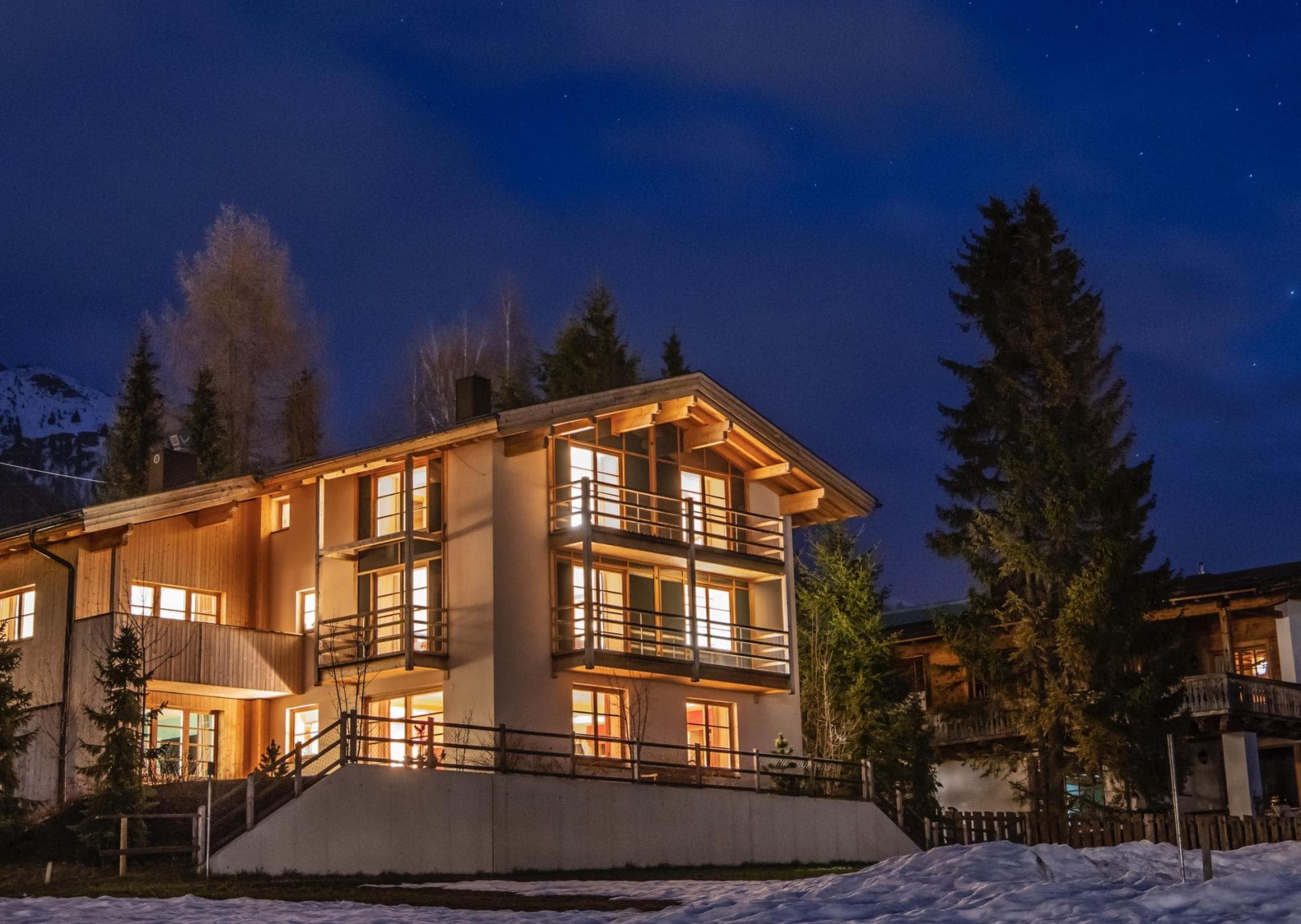 Chalet exterior at night with multiple private balconies and mountain views