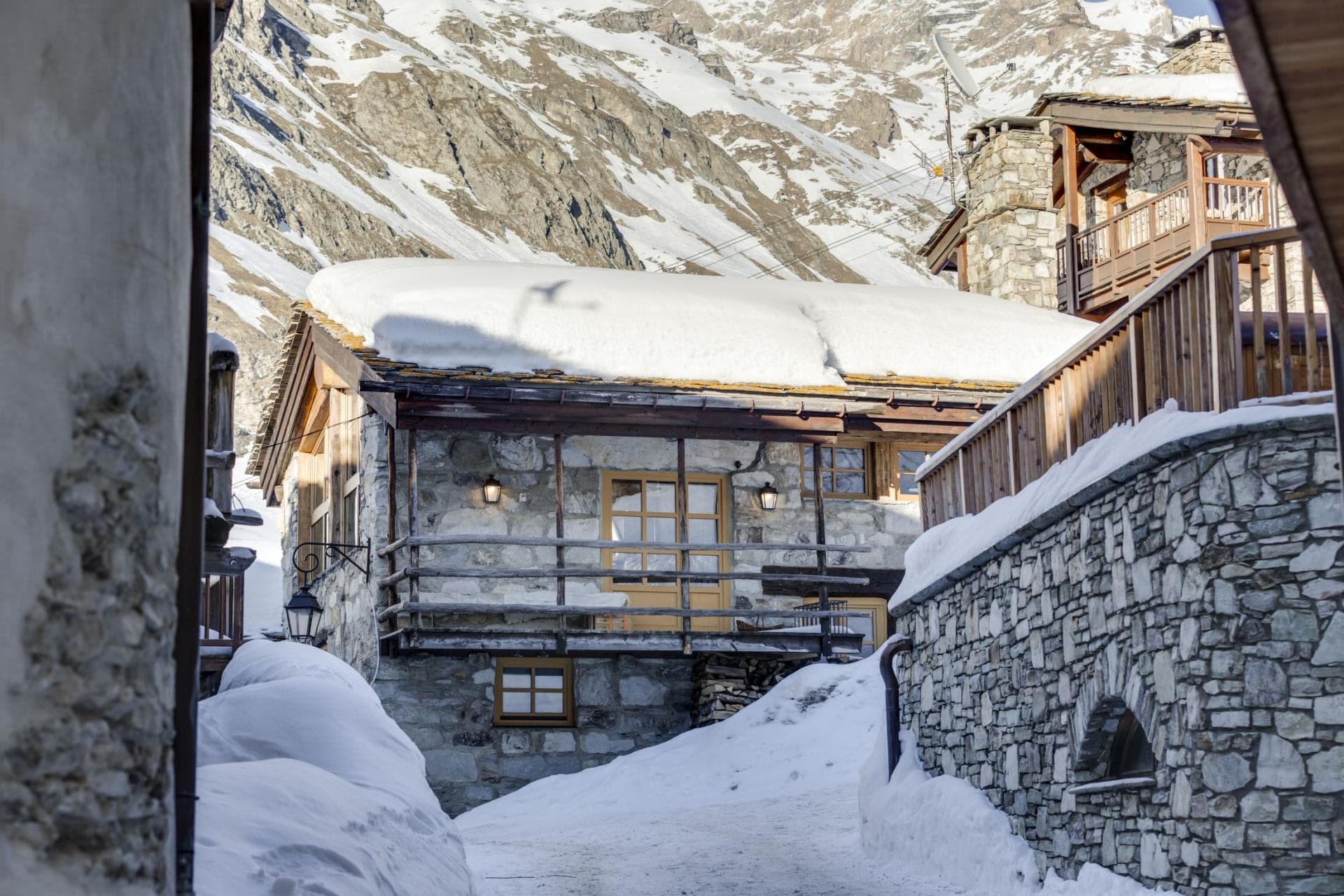 Stone chalet exterior with wooden balcony and mountain backdrop
