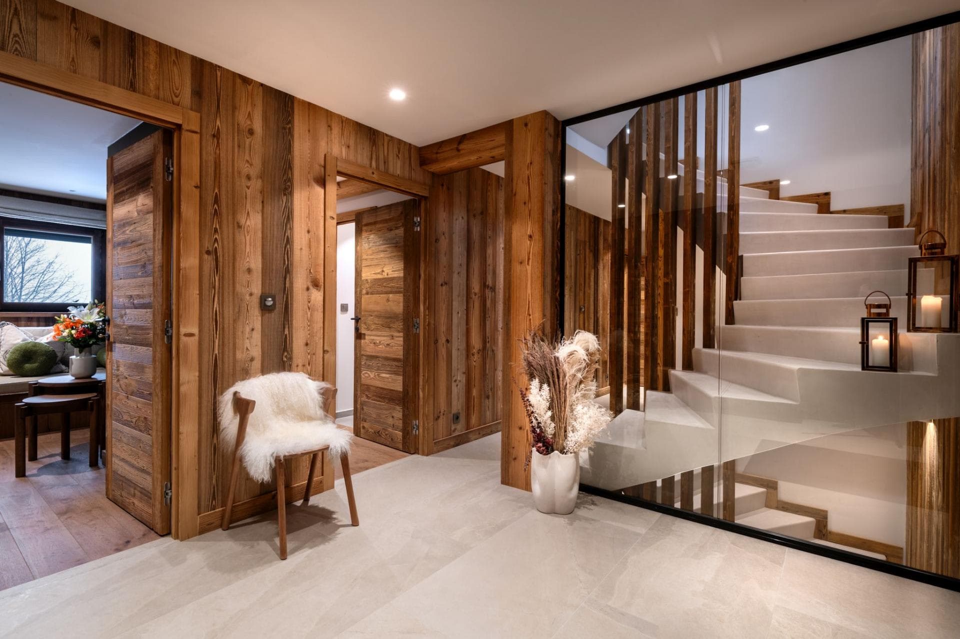 Lower level hallway with stone floors and glass-enclosed staircase