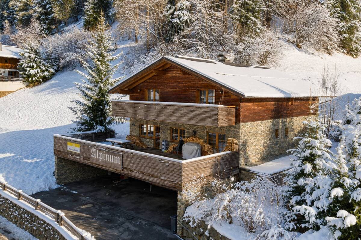 Chalet exterior in snow with a broad terrace and mountain backdrop